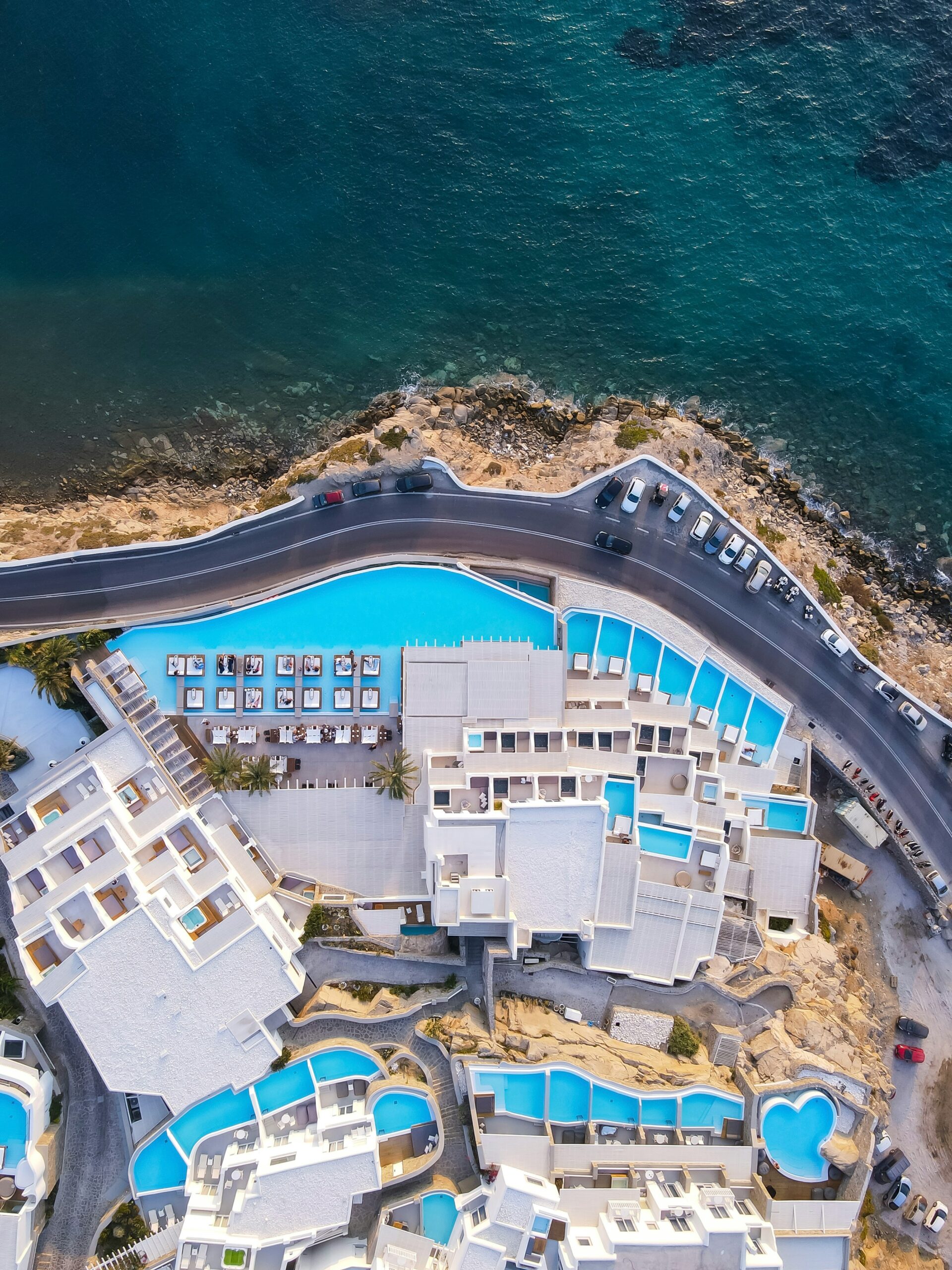A birds-eye view captures the elegant curves of a luxury hotel's pools alongside the tranquil Mediterranean Sea.