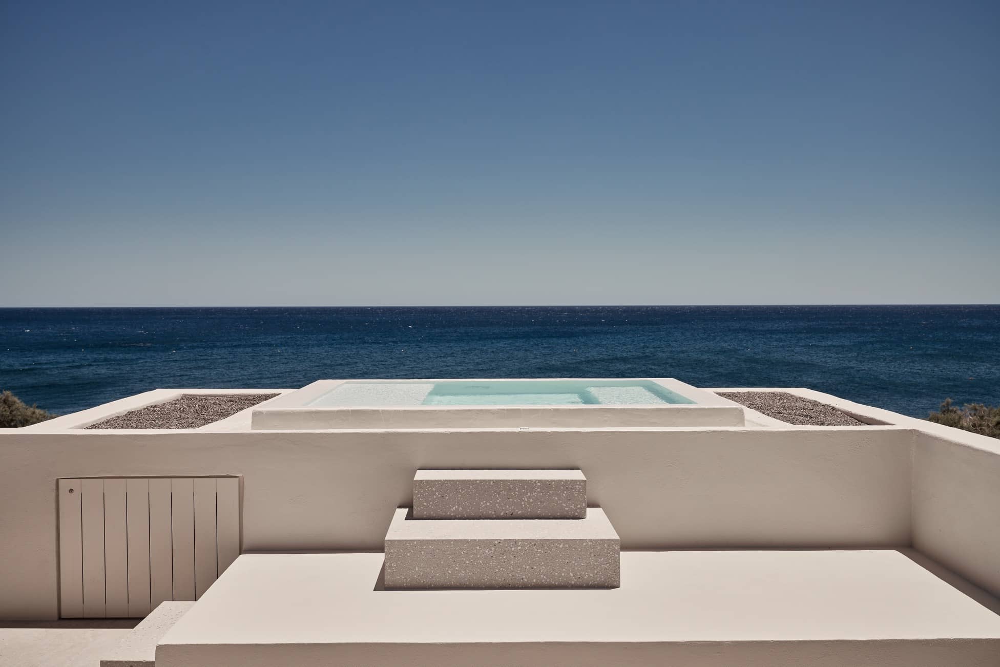 Minimalist rooftop terrace with a rectangular pool overlooking the sea.