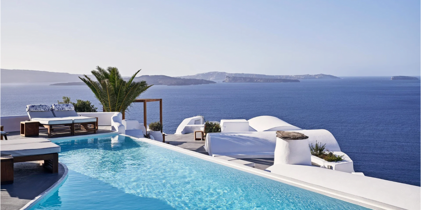 An infinity pool at a luxury hotel with lounge areas overlooking the sea and distant islands.