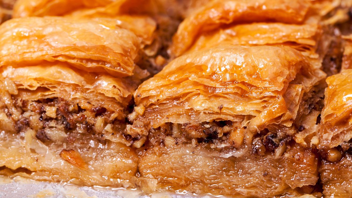Close-up view of Greek baklava, showcasing the golden, flaky pastry layers glistening with syrup, with the pieces cut into diamonds, ready to be served.