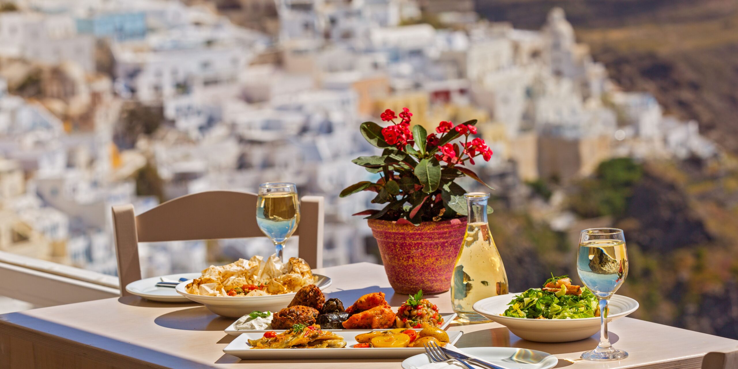 a table with greek food on it and a pot of flowers
