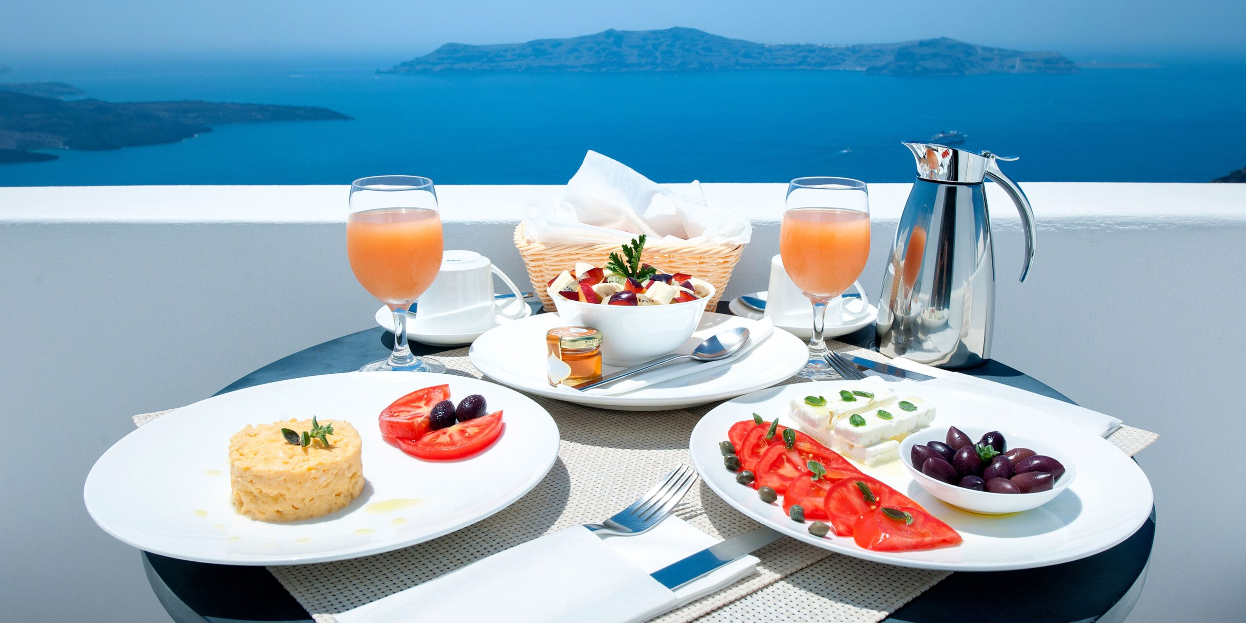 dishe with greek food on plates on a white table overlooking the agean sea