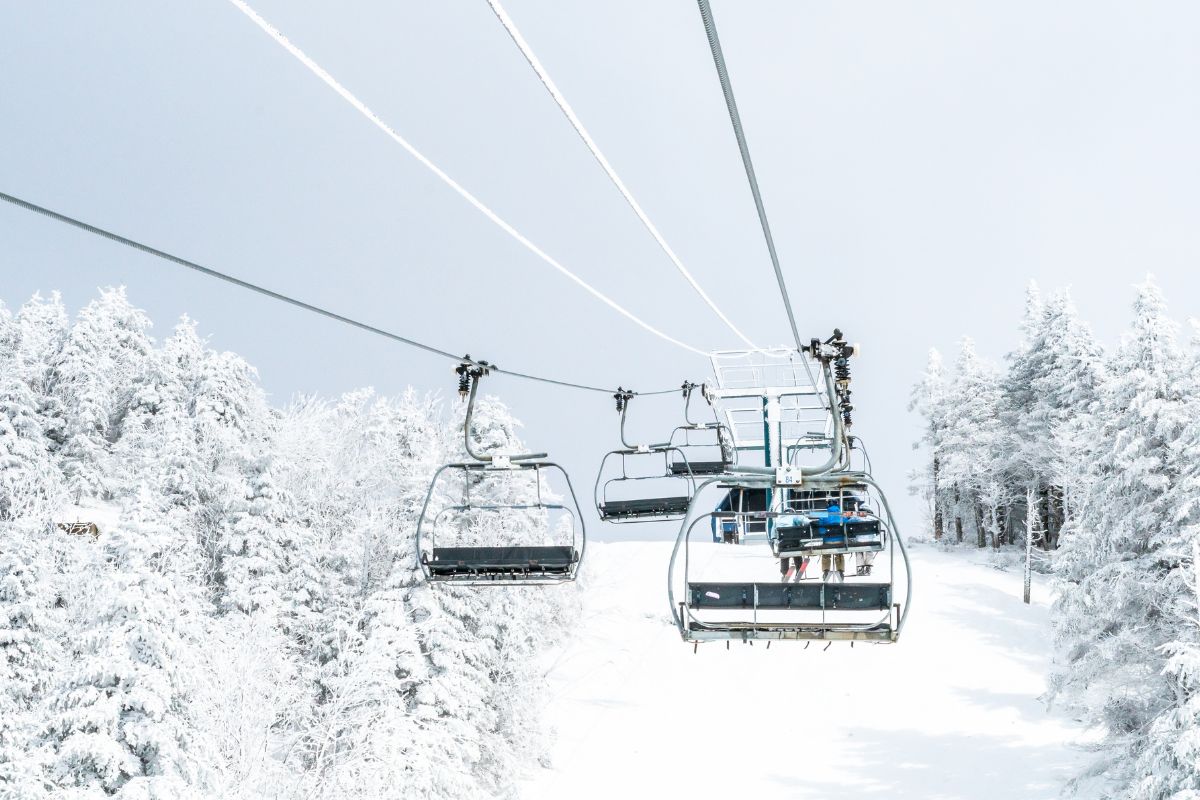 A ski lift carrying skiers above snow-covered trees and slopes, capturing a serene winter scene in the mountains of Greece.
