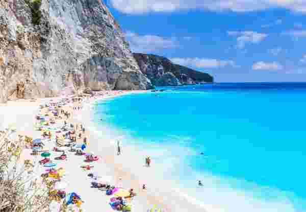 A stunning beach in Lefkada island in Greece with turquoise waters and white cliffs, filled with people enjoying the sun and sea. Lefkada_best greek islands to visit in september_feature