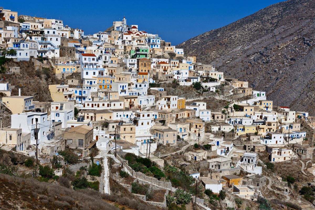View of a traditional village on Karpathos Island, with white-washed houses and colorful accents nestled on a hillside.
