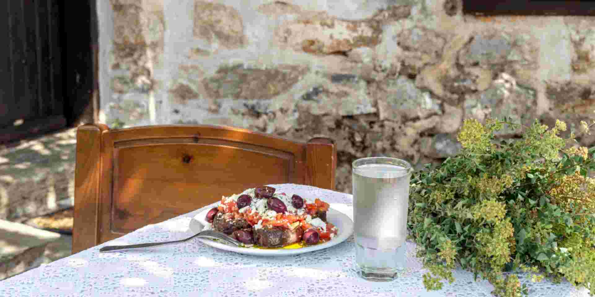 National Cretan, Greek snack (dakos). Crackers with grated tomatoes, feta cheese, oregano, olives and olive oil on a table in the patio close-up_cretan diet Cretan food_feature_cretan diet