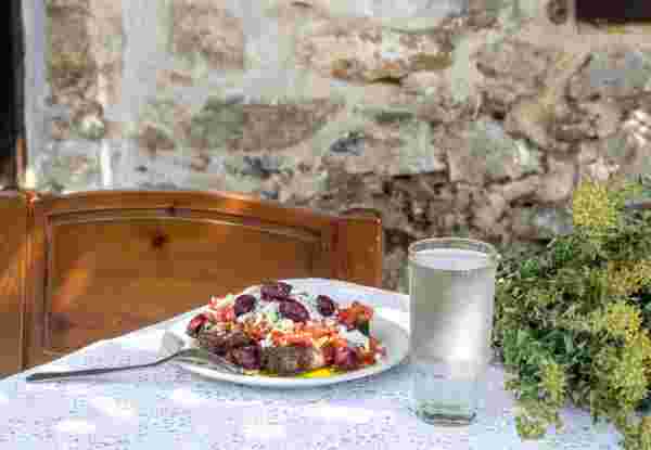 National Cretan, Greek snack (dakos). Crackers with grated tomatoes, feta cheese, oregano, olives and olive oil on a table in the patio close-up_cretan diet Cretan food_feature_cretan diet