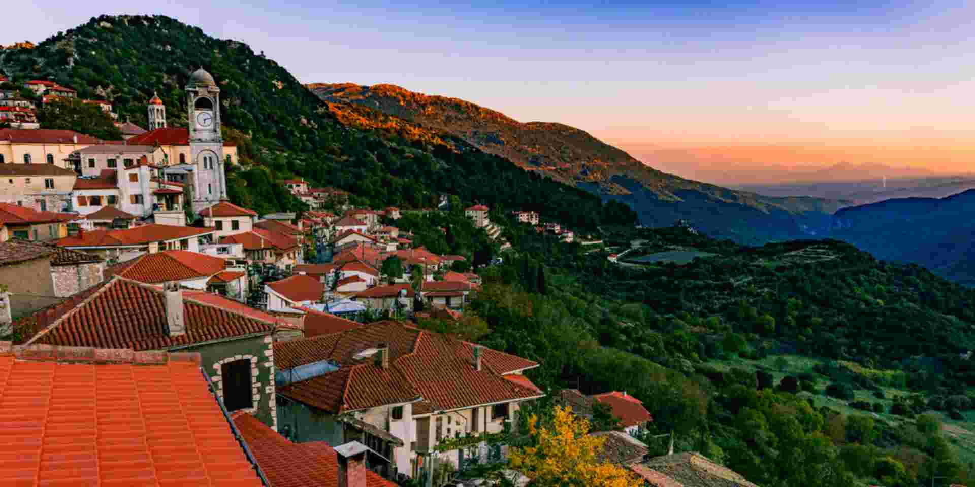 A breathtaking view of the sunset over Dimitsana, a picturesque mountain village in the Peloponnese region of Greece. The vibrant colors of the sky beautifully contrast with the serene landscape, capturing the tranquil essence of this charming village. Dimitsana Arcadia_Mountainous Villages in Greece_feature