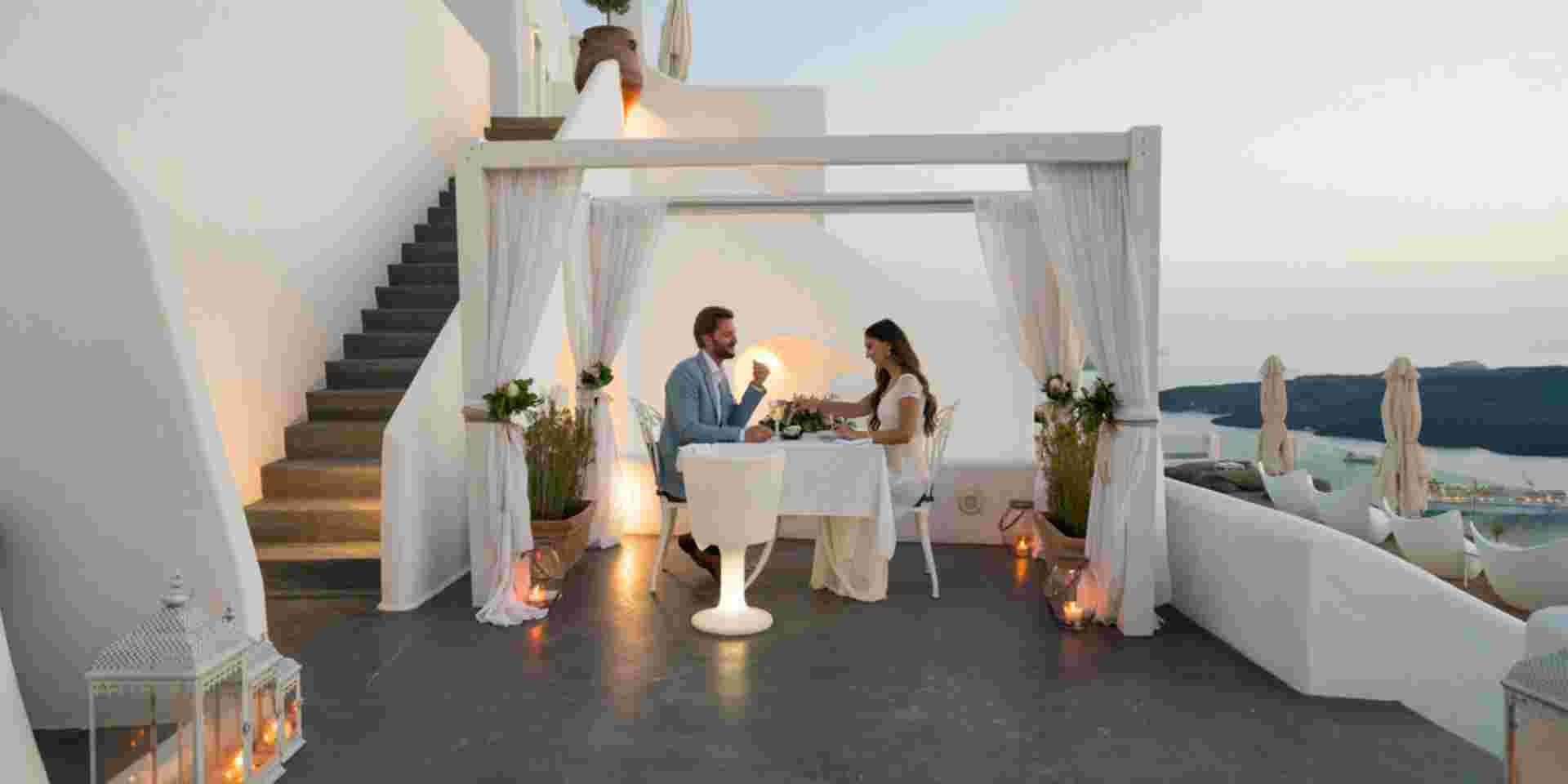 couple having candlelight dinner on romantic terrace with seaview honeymoon, vacation santorini honeymoon_feature