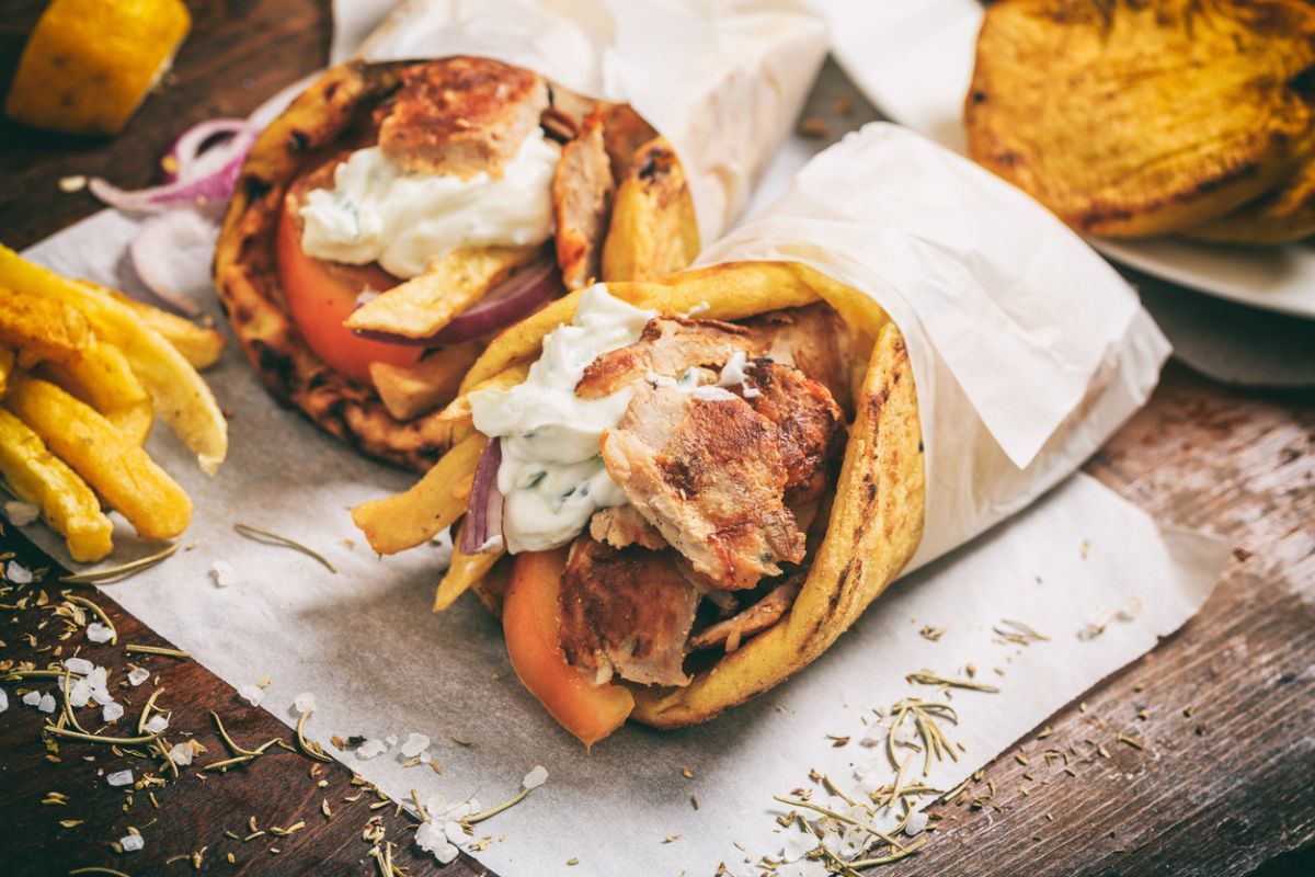 Greek gyros wraped in a pita bread on a wooden background_traditional greek food
