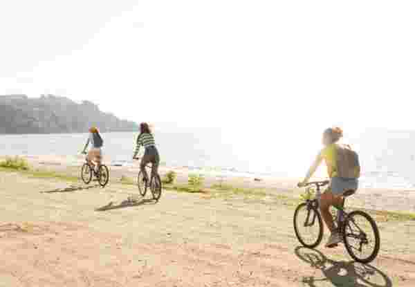 Photo of a smiling teenage girls, using bicycles to commute to the beach Family bicylce routes in greece_feature