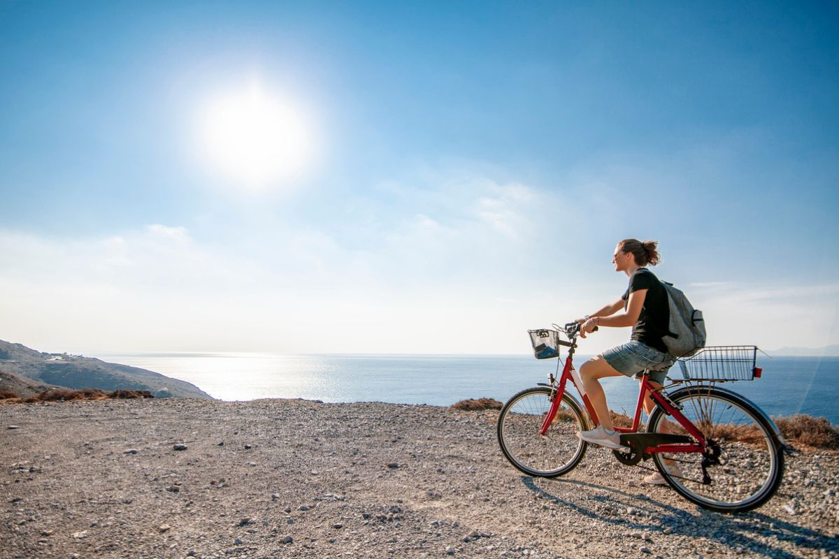 Young beautiful girl woman travels by bicycle on a mountain landscape on the beach in the sun, tourism and leisure concept, Greece, Kos