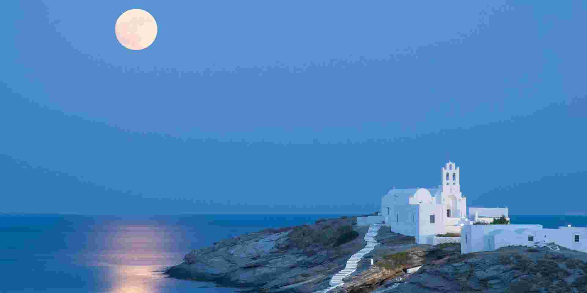 A summer picture of the island Sifnos with the full moon and its reflections on the Aegean Sea. The famous church of Panagia Chrysopigi on the foreground. Sifnos_feature