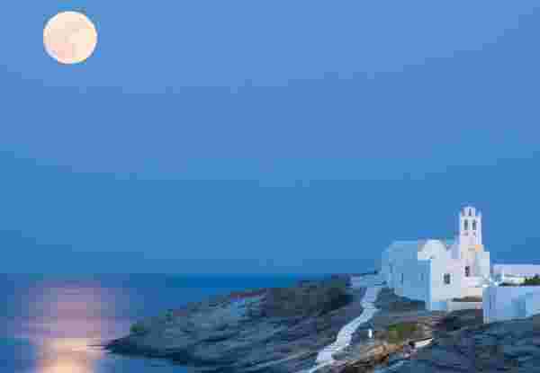 A summer picture of the island Sifnos with the full moon and its reflections on the Aegean Sea. The famous church of Panagia Chrysopigi on the foreground. Sifnos_feature