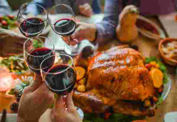 Group of unrecognizable people toasting with wine during Thanksgiving dinner at dining table. Greek christmas food_feature