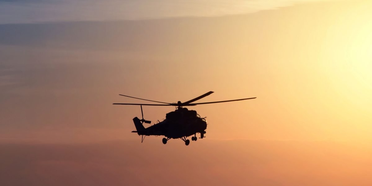 helicopter during sunset over the sea with orange and yellow skies