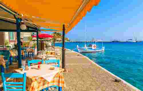 Tables with chairs in traditional Greek tavern in Kokkari town on coast of Samos island, Greece