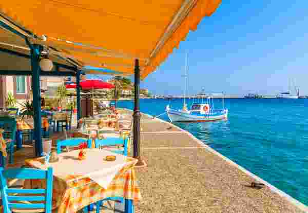 Tables with chairs in traditional Greek tavern in Kokkari town on coast of Samos island, Greece
