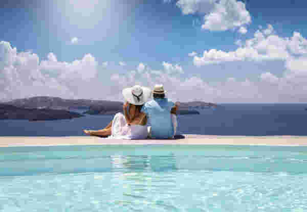 A elegant couple in summer clothes sits by the pool and enjoys the view to the mediterranean sea in Greece during their summer holidays A elegant couple in summer clothes sits by the pool and enjoys the view to the mediterranean sea