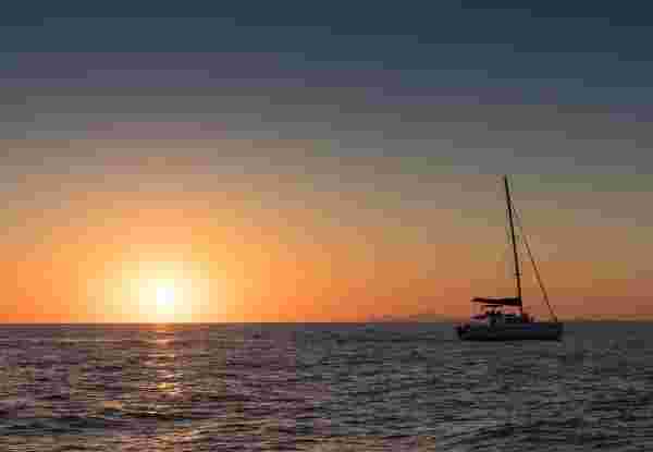 Beautiful sunset in Oia, Santorini, seen from the sea with silhouette of catamaran. Beautiful sunset in Oia, Santorini, seen from the sea with silhouette of catamaran.