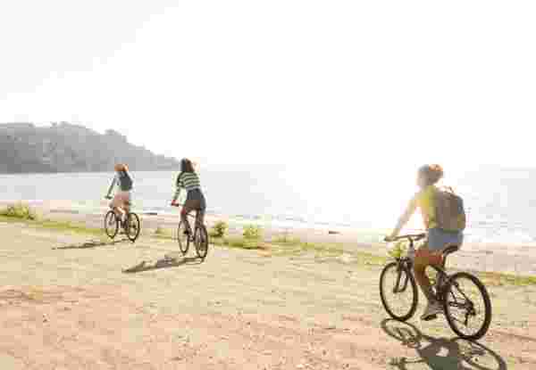 Photo of a smiling teenage girls, using bicycles to commute to the beach greece with kids guide_feature