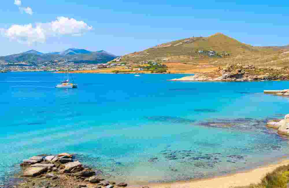 Catamaran boat sailing on azure sea in Monastiri bay on Paros island, Greece