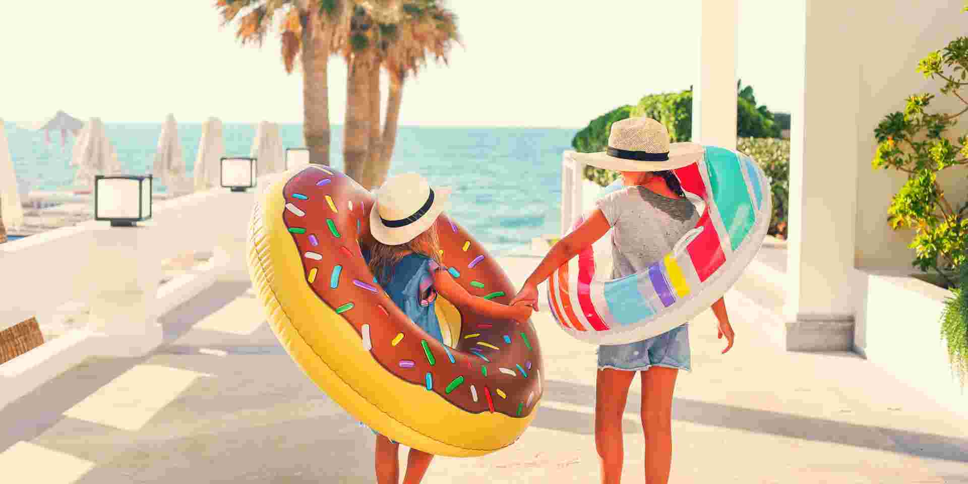 Two small girls with inflatable toys on the beach. Summer vacation and traveling concept What to Do in Greece with Kids_feature