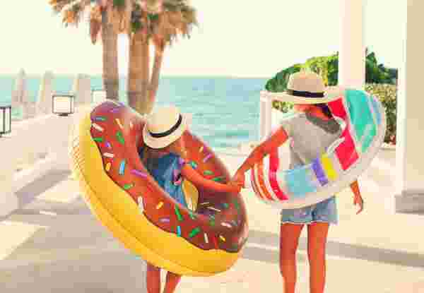 Two small girls with inflatable toys on the beach. Summer vacation and traveling concept What to Do in Greece with Kids_feature