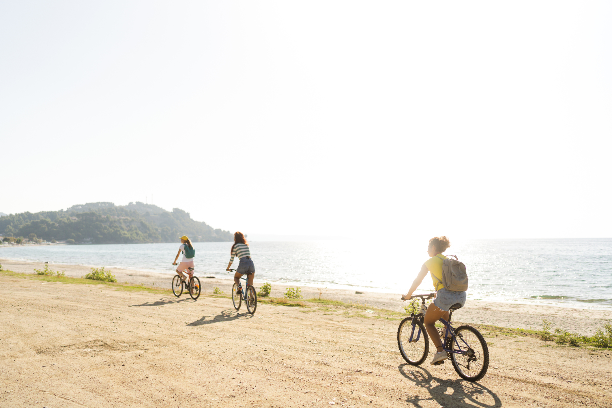 Photo of a smiling teenage girls, using bicycles to commute to the beach