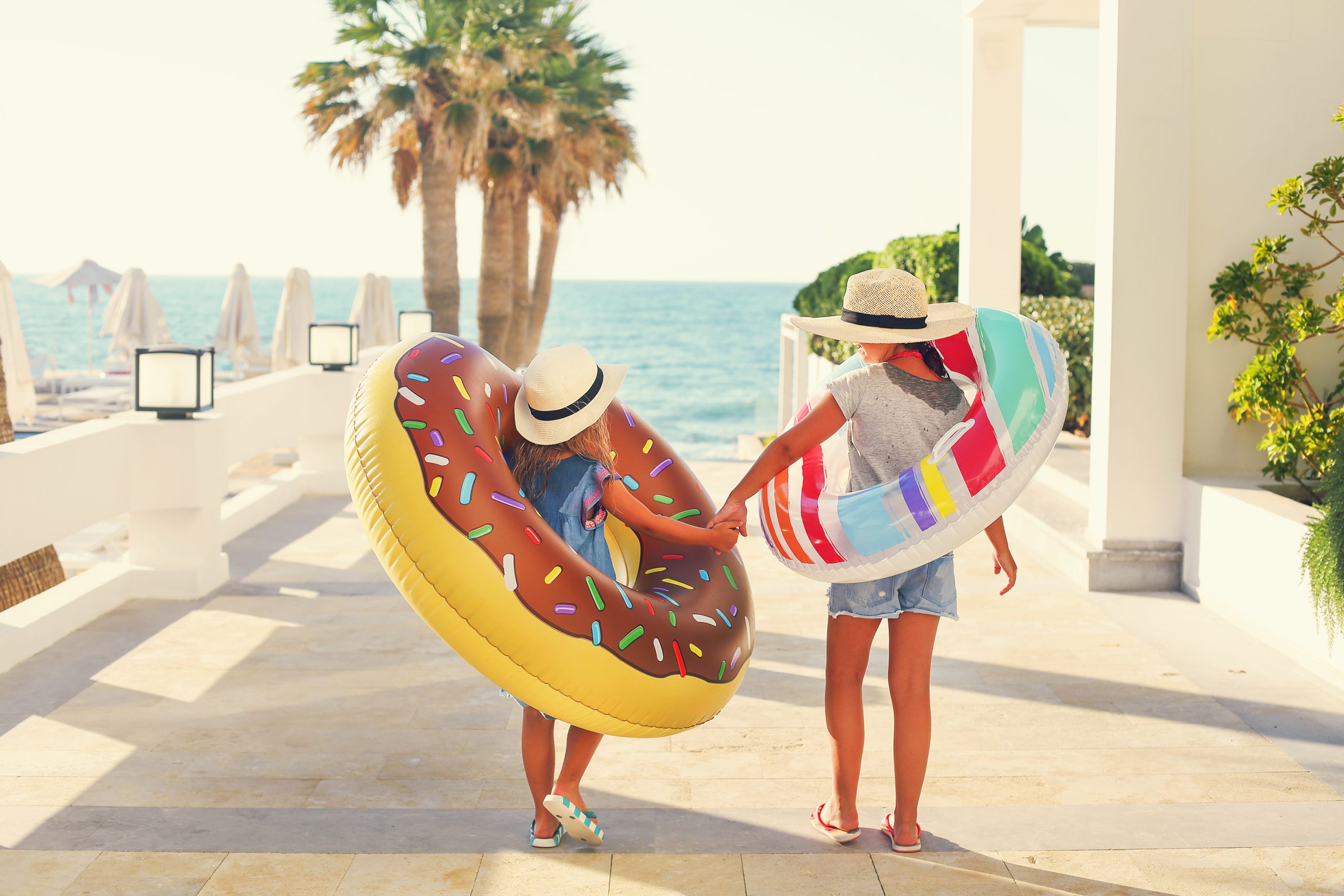 Two small girls with inflatable toys on the beach. Summer vacation and traveling concept