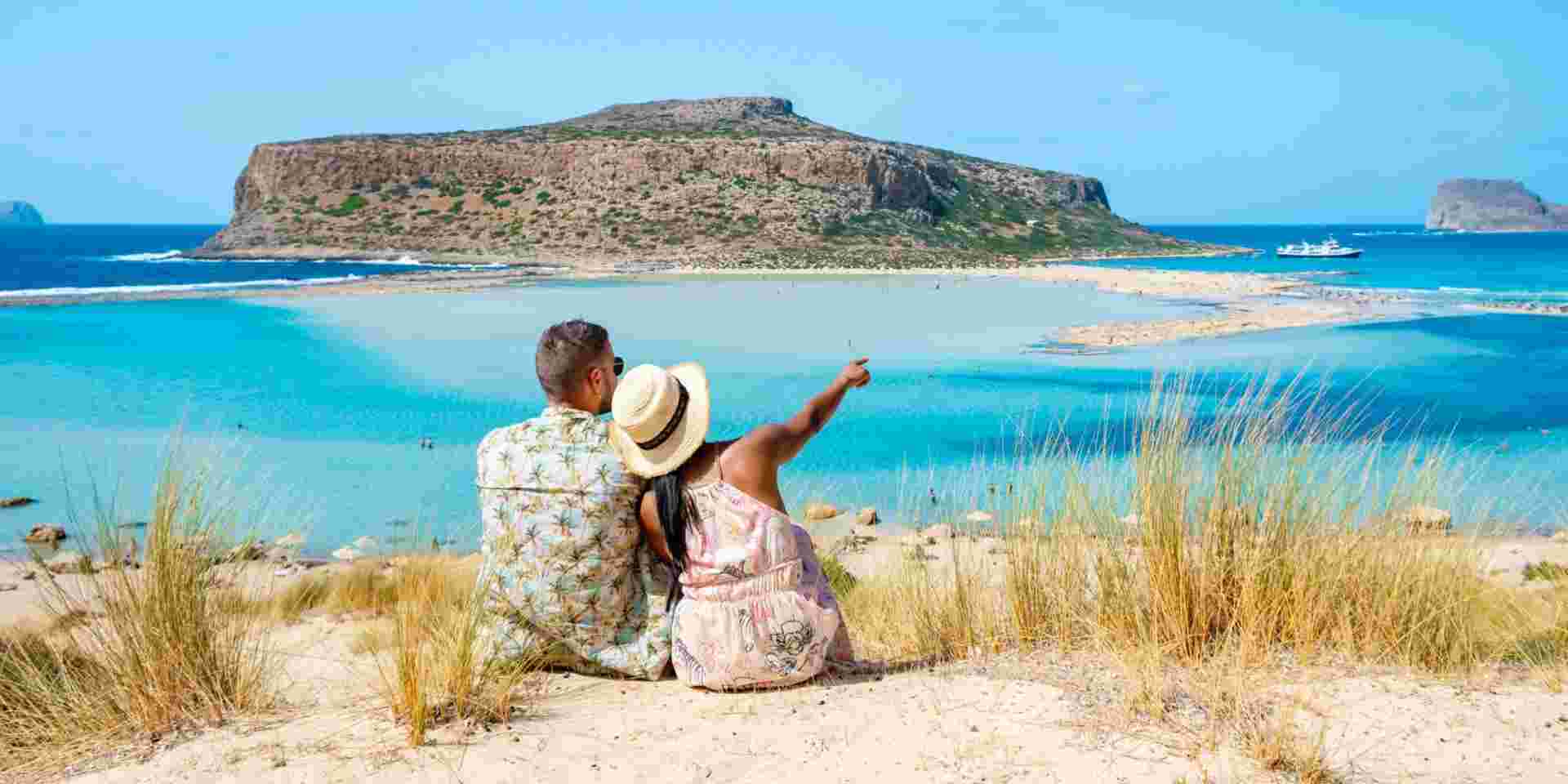 Crete Greece, Balos lagoon Crete island, Greece. Tourists relax at the crystal clear ocean of Balos Beach. a couple of men and a woman visit the beach during a vacation in Greece on a sunny day crete couple_romantic things to do in greece_feature