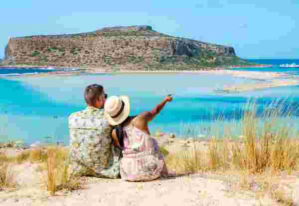 Crete Greece, Balos lagoon Crete island, Greece. Tourists relax at the crystal clear ocean of Balos Beach. a couple of men and a woman visit the beach during a vacation in Greece on a sunny day crete couple_romantic things to do in greece_feature