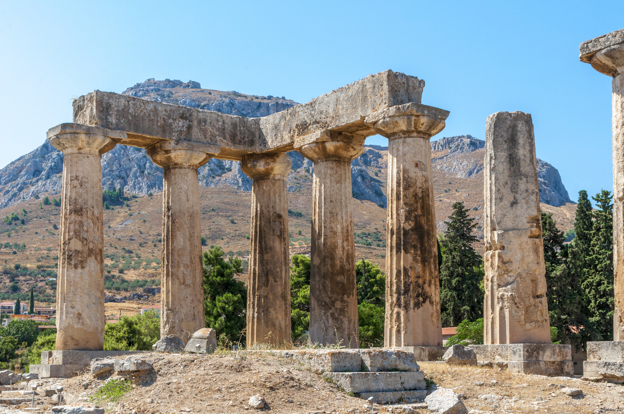 The ruins of the ancient temple in ancient Corinth against a backdrop of scenic mountains. Peloponnese. Greece