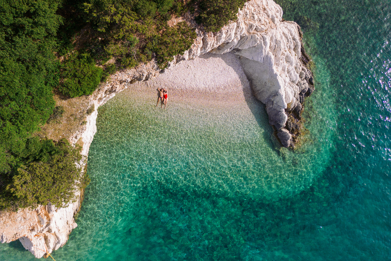 Couple enjoying vacation and relaxing alone on the beautiful beach. Young woman and man in love sunbathing and color of water is amazing. Filiatro beach, Ithaca Island, Greece