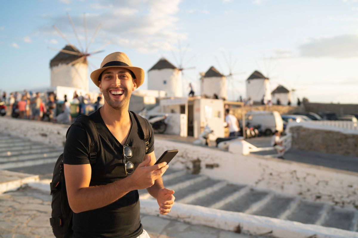 Portrait Of A Young Man Using Smartphone In The Streets Of Mykonos.