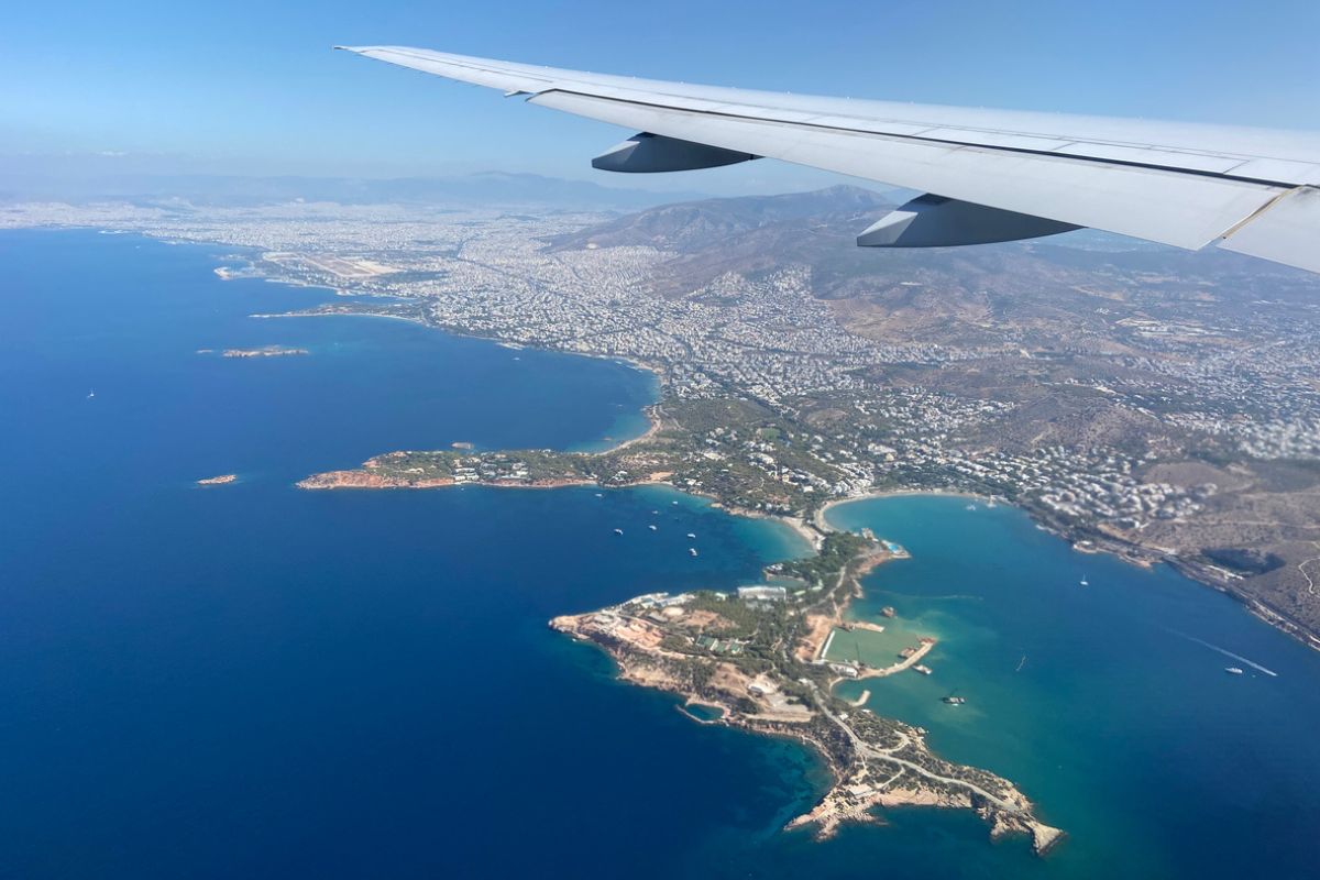 Aerial view from an airplane of an airplane wing flying above the Greek coastline and the Aegean Sea while approaching Eleftherios Venizelos Athens International Airport in Greece