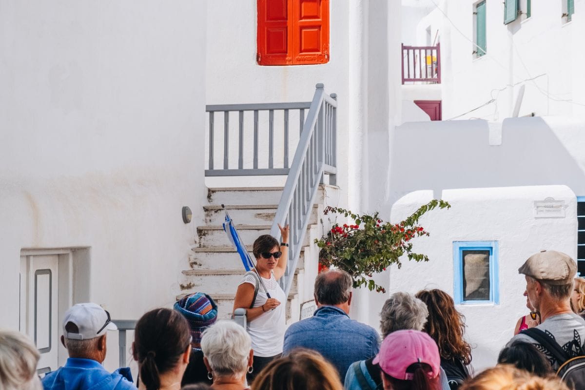 Mykonos Town, Greece - September 23, 2019: Tour guide talking to a group of tourists on a street in Hora (also known as Mykonos Town), the islands well-preserved port and capital. Selective focus.