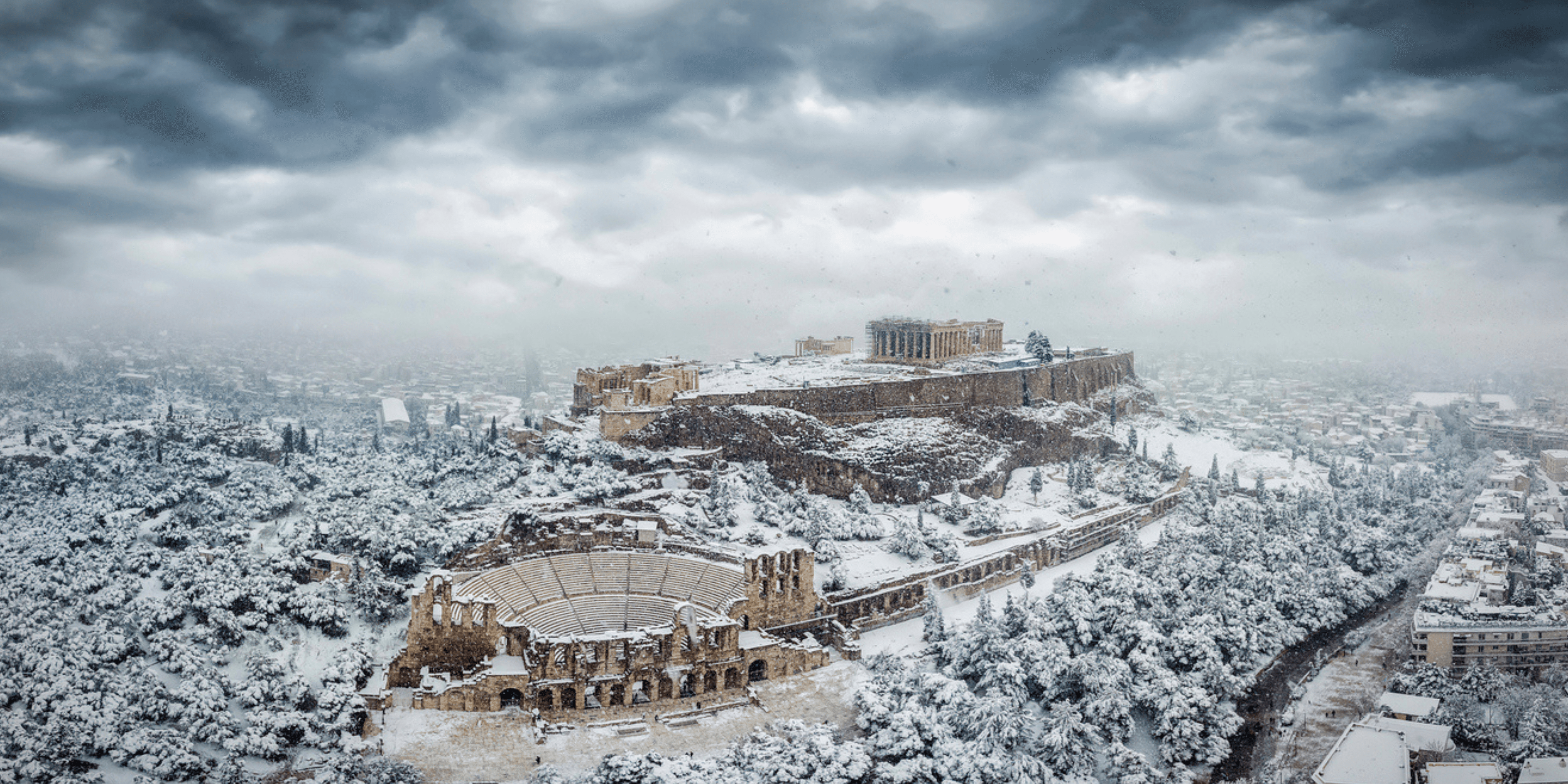 The Parthenon Temple and the Herodion Theater at the Acropolis of Athens, Greece, with ice and snow during a winter snowstorm