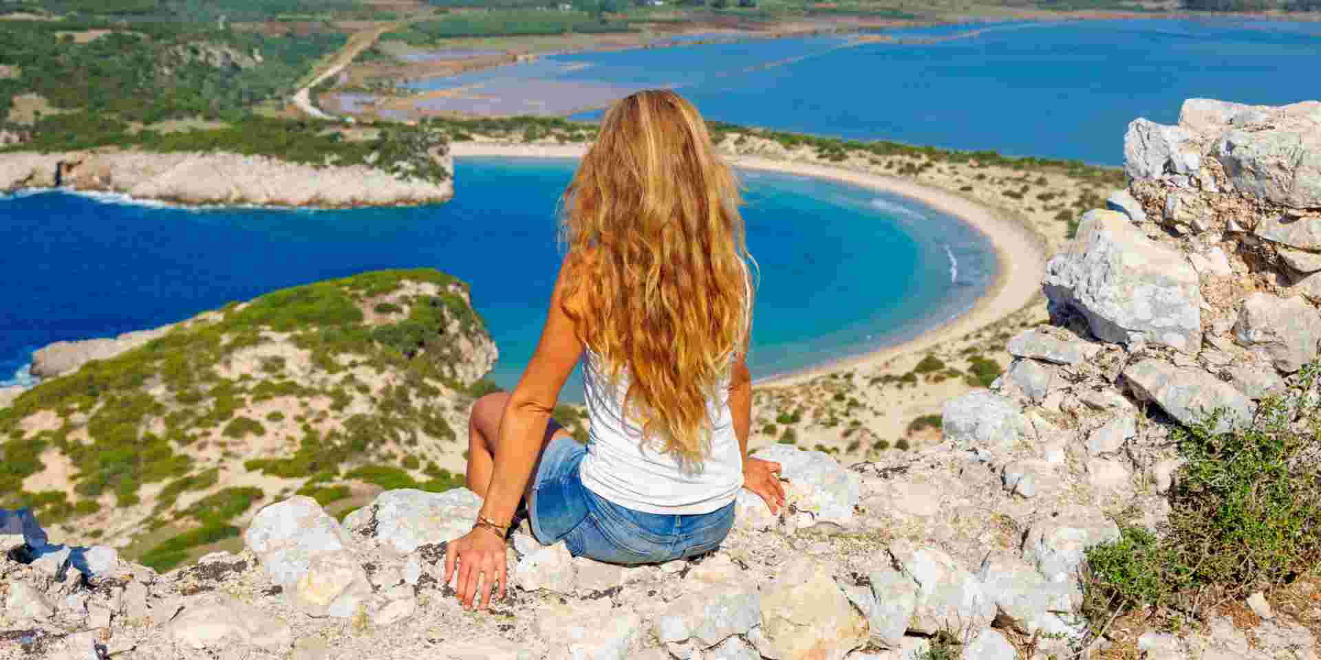 Beautiful Woman Admiring a Stunning Beach in Greece - Travel & Adventure best greek island for solo travel greece_feature