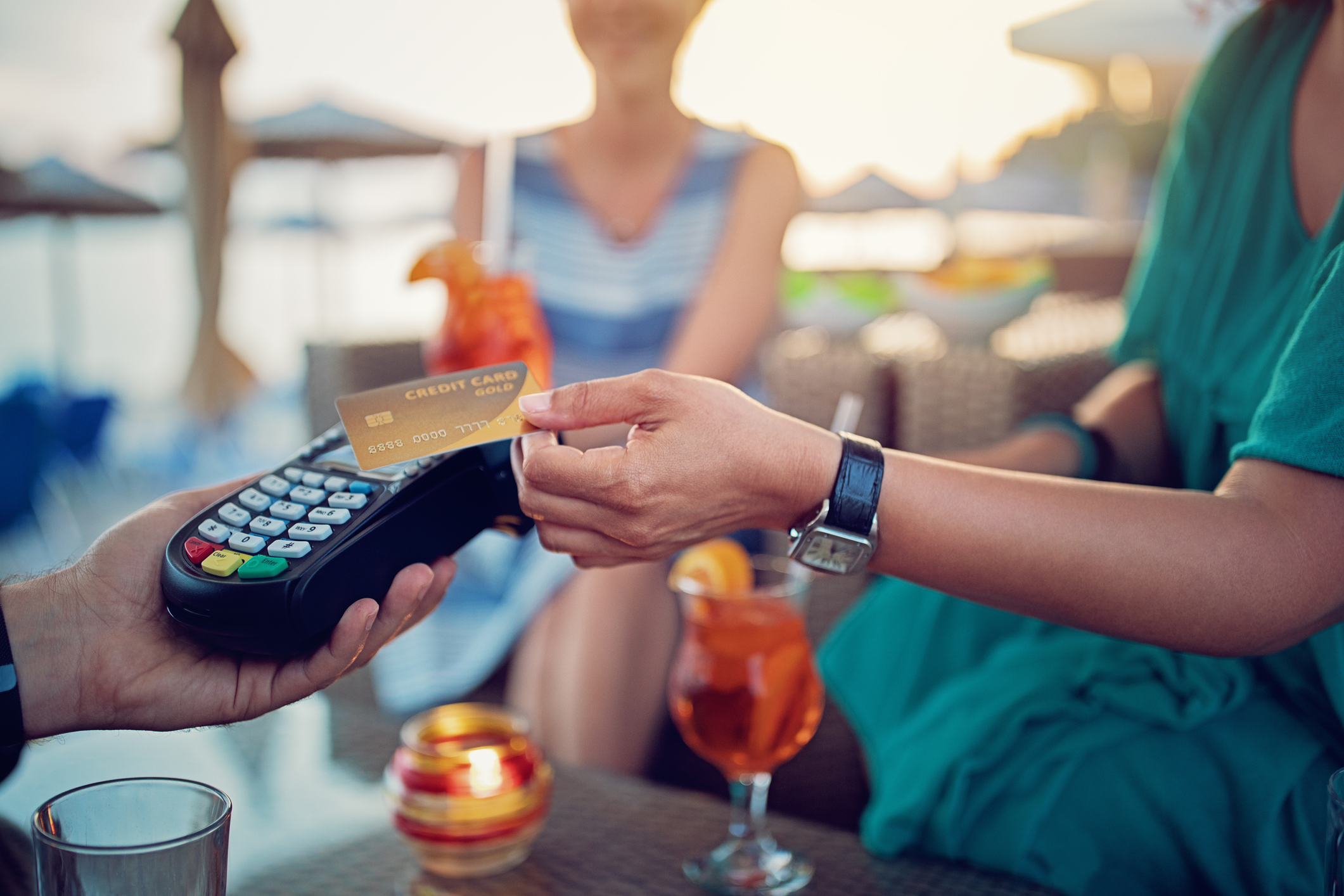 Girlfriends are paying their cocktails on the beach bar using contactless credit card