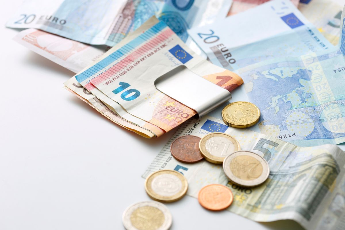 Euro banknotes and coins on a white surface, showing European currency commonly used for travel and international exchange.