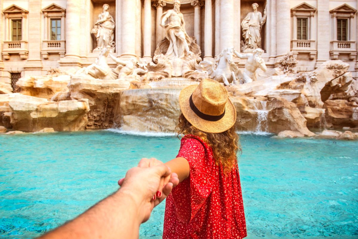 Romantic woman and man holding hands and walking to Trevi Fountain Rome, Italy.