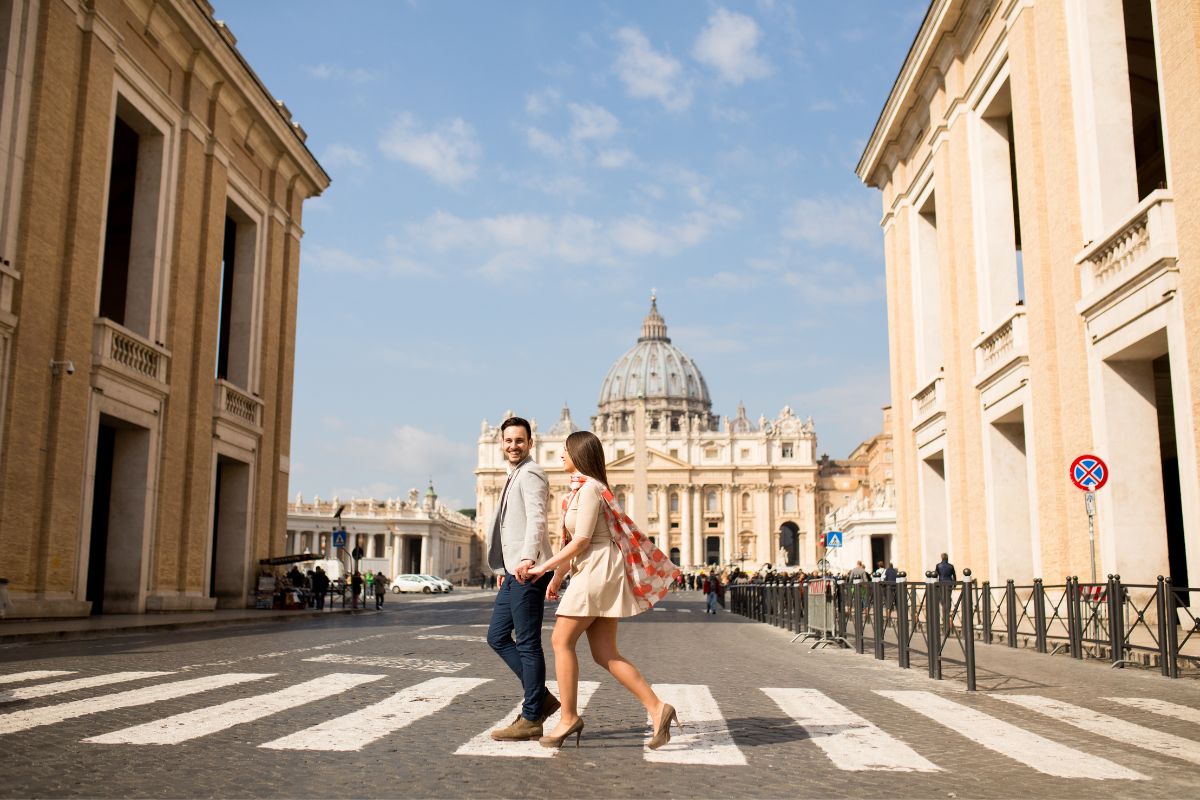 Couple walking hand in hand near St. Peter’s Basilica in Vatican City, enjoying a romantic moment in Rome.