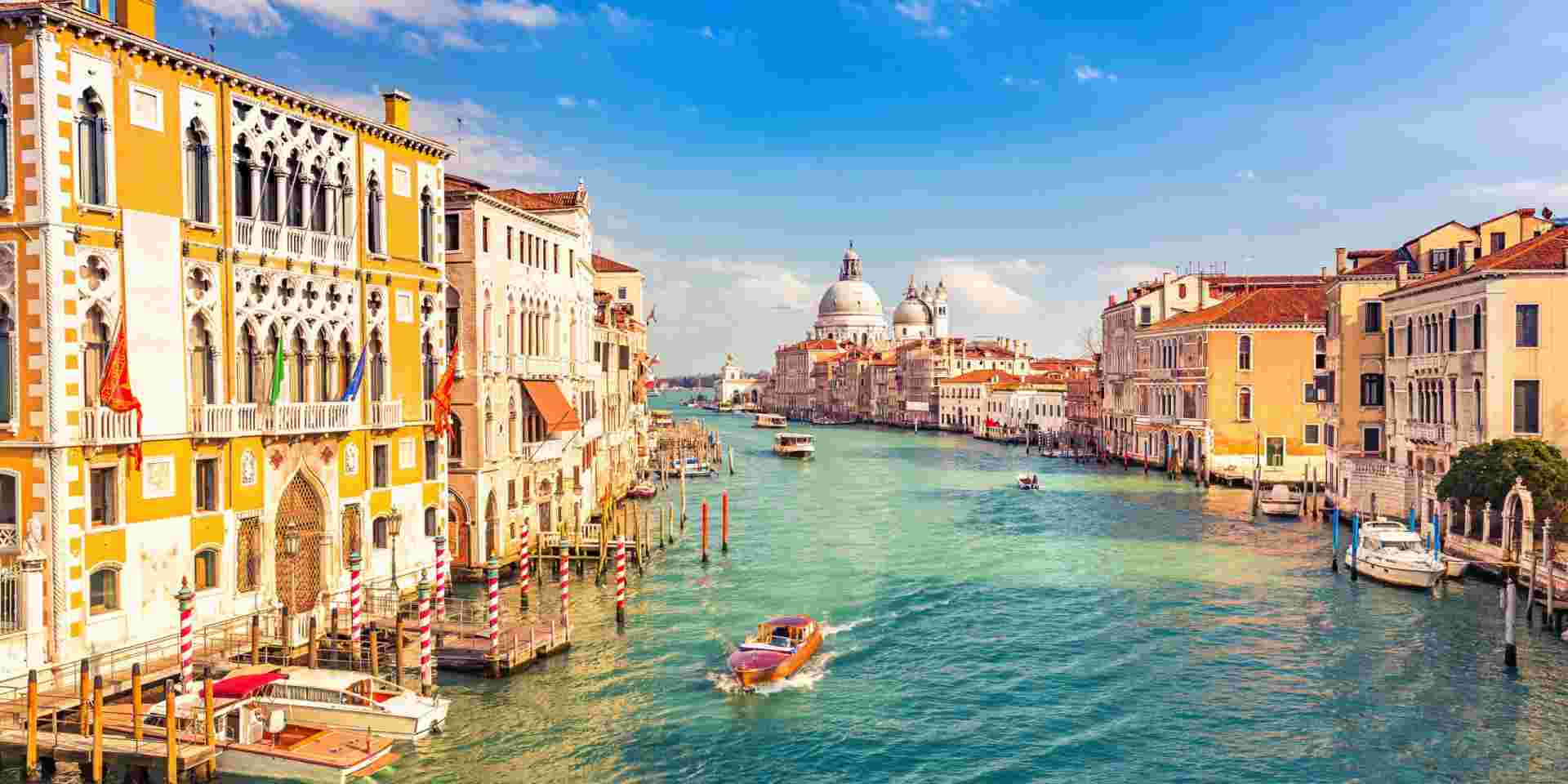 A view of Venice’s Grand Canal with historic buildings, boats, and the Basilica di Santa Maria della Salute in the background. Venice_best time of year to visit greece and italy