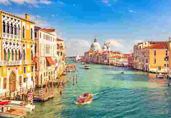 A view of Venice’s Grand Canal with historic buildings, boats, and the Basilica di Santa Maria della Salute in the background. Venice_best time of year to visit greece and italy