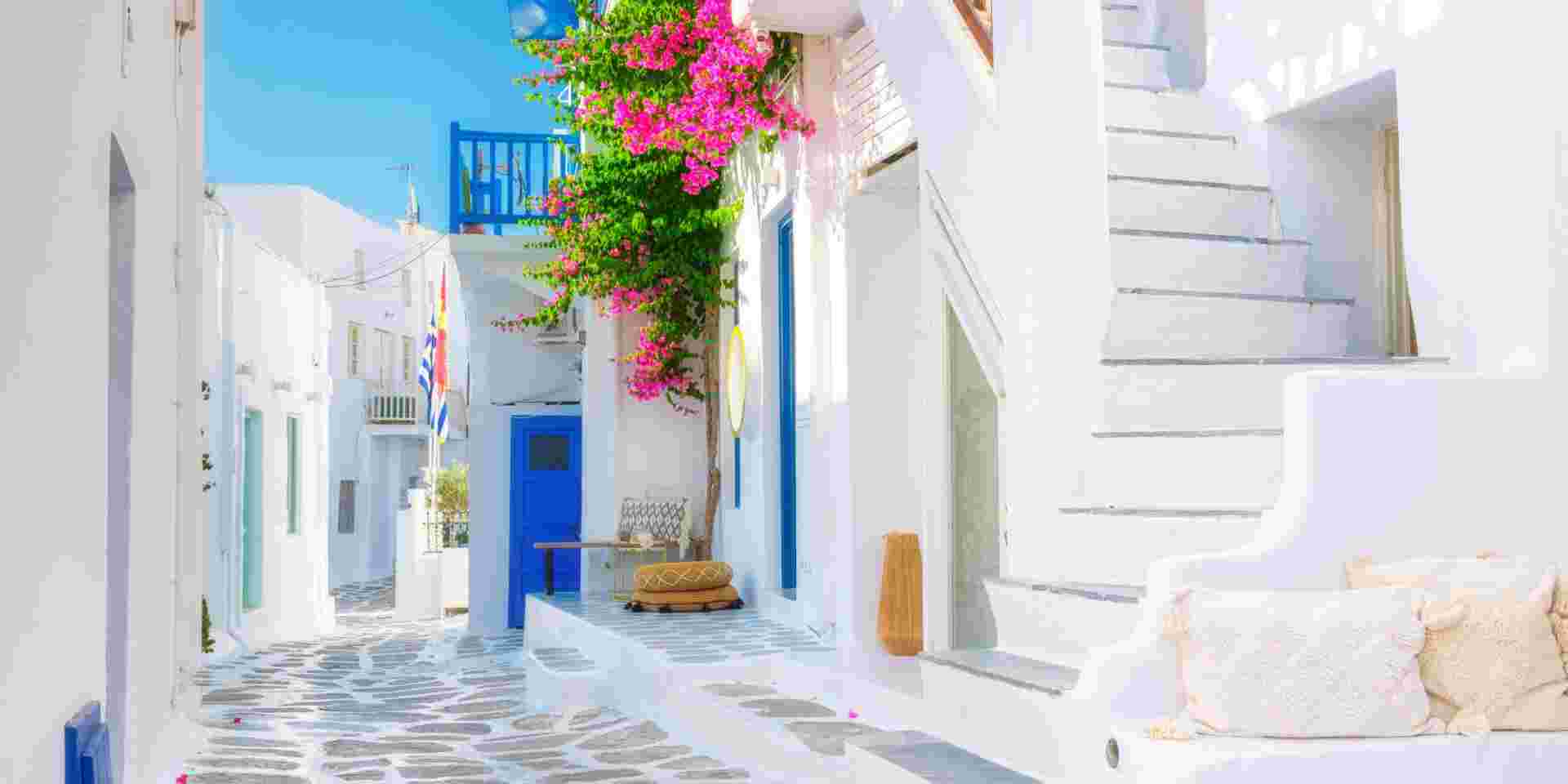 The island of Mykonos, Greece. Streets and traditional architecture. White-colored buildings and bright flowers. Travel photography. mykonos chora_feature
