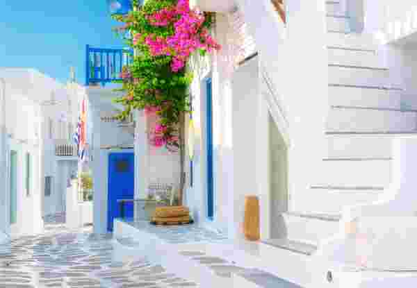 The island of Mykonos, Greece. Streets and traditional architecture. White-colored buildings and bright flowers. Travel photography. mykonos chora_feature