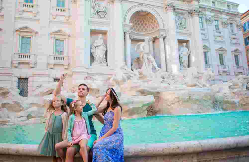Happy family trowing coins at Trevi Fountain, Rome, for good luck. Little girls and parents making a wish to come back.