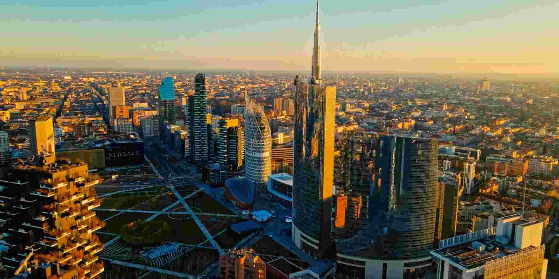 A picturesque aerial view of Milan with the sun setting, highlighting diverse architecture that juxtaposes traditional and contemporary styles. Milan_Feature