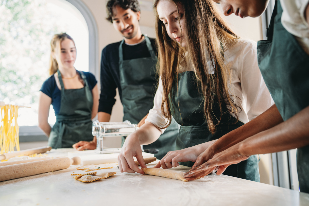 People are making homemade ravioli during a cooking class. They are preparing ravioli together.